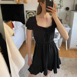 Söt svart klänning NAKD  - En klänning med volanger nertill och puffärm på axlarna 🩷  Framtill är en rosett. Skön och luftig till sommaren 🫶🏼 Säljer då den blivit för kort för min smak. Är 170.