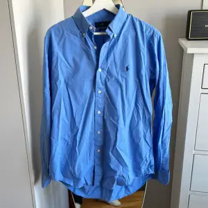 Ljusblå Ralph Lauren skjorta i använt men bra skick. Någon liten fläck, därmed billiga priset. Dock inget som syns vif användning. Säljes då den ej kommer till användning längre. Nypris 1700.