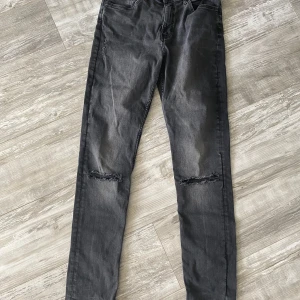 Jeans - Svarta ”slitna” jeans. Gjorda hål vid knä. Köpta så. Så gott som nya. Slim modell. Stl 170