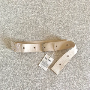 Djerf Avenue Denim Butterfly Belt Cream - Otroligt fint skärp med en avtagbar fjäril från Djerf Avenue. Supersnygg accessoar till alla möjliga stylingar. Ny med tags kvar. Ordinariepris 999kr. Storlek one size.