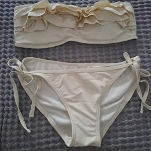 Off white bikini sett från bikbok Off shoulder det går att sätta dit ett band om man vill det går även att ta ut inläggen,överdelen är använd fåtal gånger. Liten defekt på spännet (se sista bild) SKICKAR EJ BILDER MED BIKININ PÅ!!!!