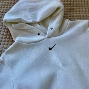 Nike Vintage Hoodie White - Mysig stil med denna klassiska vita Nike-huva! Med material av bomull och ikonisk Nike-logotyp är denna huva perfekt för träning eller vardagsbruk.