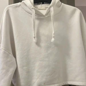 Vit långärmad kroppad hoodie.  - Nästan helt ny då jag bara använt den två gånger. Säljer den då den är för liten. Inga skador och i väldigt gott skick. 