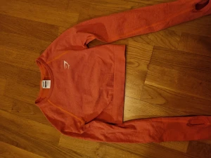 Orange Gymshark träningstopp  - Den är i storlek xs och knappt använd. Ärmarna är långa och har hål för tummen. 
