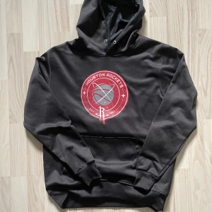 Svart Houston Rockets hoodie - 249kr - Svart Houston Rockets hoodie i storlek medium. 100% bomull. Rött cirkel tryck med vit/grå detaljer på mitten av bröstet. Snörena till luvan är klippta! För mått/fler bilder skriv privat.