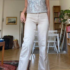 Beiga kostymbyxor  - Beiga kostymbyxor med lite bootcut. De är insydda i midjan så har ingen exakt storlek men uppskattar M. Lite smutsiga i ena nederkanten (se sista bilden), men i övrigt bra skick.