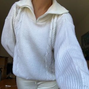 Stickad tröja - Vit stickad tröja med hög krage och dragkedja. Lite noppig men annars bra skick. Väldigt varm och skön. Finns inga lappar med storlek eller märke men uppskattar ca storlek M