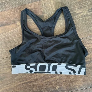 Svart sport-bh med grå resår - Säljer en svart sport-topp, inköpt från stadium. De har inga inlägg men har ändå bra support. Välanvänd, och i väldigt fint skick, utöver att texten börjar försvinna lite och att reformen har några små märker (dessa påverkar dock ingenting, utan är bara skönhetsfel). 