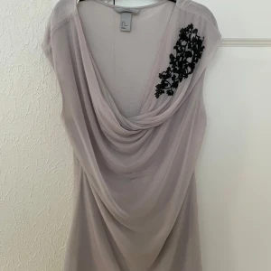 Blus/tröja - Använd flertals gånger men ändå i jättebra skick.  Den är grå/beige aktig med fina svarta detaljer. Svårt att sätta ord på färgen.  Jätte bra till för middagar eller om man ska på uteservering, fin och klassiks tröja!