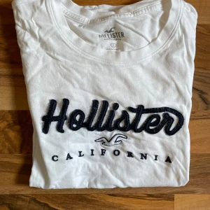 vit hollister t-shirt  - fått av min syster för länge sedan så är väl använd av oss båda. finns tecken av användning men är i okej skick. storlek s i märket hollister. tröjan är vit med mörkblått tryck. hör av dig för mått/fler bilder eller andra funderingar:)