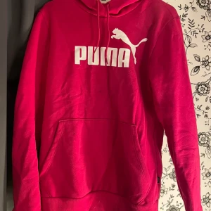 Röd hoodie från Puma - Säljer en snygg röd hoodie från Puma. Den är i storlek S och har en stor vit Puma-logga på bröstet. Hoodien har en stor ficka på magen och en justerbar huva med snören. Perfekt för höst och vinter, superbekväm och stilren! 🐾