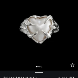 Eight of Wands Ring - Säljer en unik och vacker ring med ett hjärtformat pärlemor i mitten, omgiven av detaljerade silverklor. Ringen har en distinkt och elegant design som verkligen sticker ut. Perfekt för speciella tillfällen eller som ett statement-smycke i vardagen.