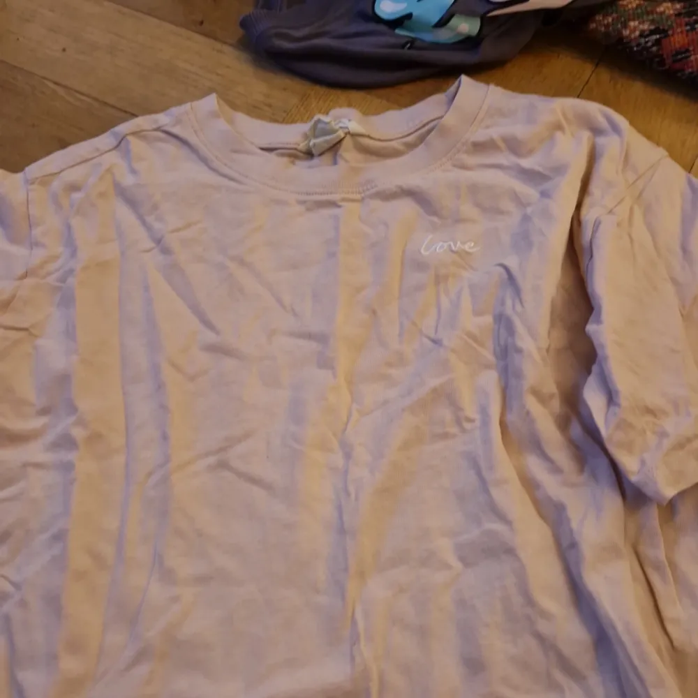 Säljer en ljus rosa t-shirt med texten 'love' broderad på bröstet. T-shirten är i bomull och har en normal passform. Perfekt för vardagsbruk eller en avslappnad dag ute. Den är i bra skick och har korta ärmar.. T-shirts.