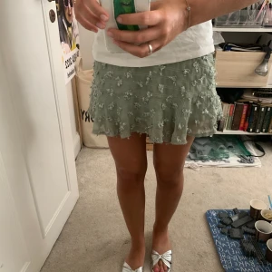 Grön kjol med mönster - Grön kjol med textur (typ små blommor) på med volang längst ner. Köpt utomlands. 