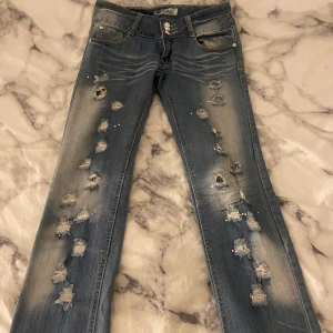 SÅ snygga lågmidjade jeans 💙 - Så coola jeans med slitningar, rhinestones i olika färger och har även ett blommigt innertyg som lossnat lite så man kan välja om man vill ha det eller inte, fint skick! 🤍 Skriv vid frågor osv! 