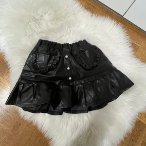 Skinn miniskirt - Den är aldrig använd så den är i ny skick, det är en Miniskirt så den är väldigt kort, materialet är skinn, den har pärlor på och fickor på framsidan.