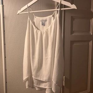 Vitt linne - Jättefint vitt linne i något slags finttyg! 💗 Linnet har en fläck på framsidan som tyvärr inte går bort, men det syns knappt när tröjan är på (se sista bild)  men linnet har även dubbeltyg (se tredje bild) som blir är en sån fin detalj 💗💓