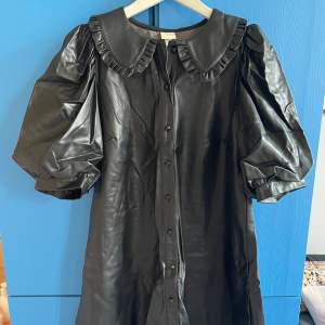 Snygg svart klänning i konstläder från H&M med puffärmar. Har endast använts en gång, är därför i väldigt fint skick! Storlek S.