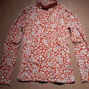 Orange och vit blommig långärmad tröja med halvpolokrage. Storlek 36 från M&S Collection, köpt på Zalando. 95% bomull, skön i tyget. Mycket bra skick, endast använd några gånger. 