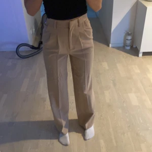 Kostymbyxor  - Beigea kostymbyxor  Ifrån Bikbok, storlek 34. Insydda i midjan men bara att sprätta upp om man vill de.