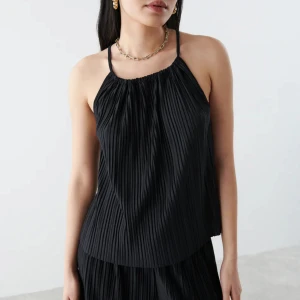 Gina tricotXBianca topp XS - Oanvänd. Denna tröja är från Bianca Ingrosso kollektion med Gina tricot, modellen är ”Tamara singlet”. Plisserat linne med tunna axelband som korsas i ryggen. Linnet är svart och har rynkade detaljer vid halsringningen. Denna tröja säljs inte längre.