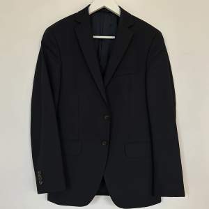 Säljer en mörkblå Oscar Jacobson ullkavaj som en del av en kostym i storlek 44. Modell Earl suit för Nitty Gritty.  Byxorna saknas tyvärr. Kavajen är i gott skick