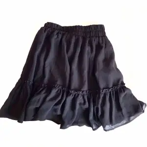 Svart kjol med volanger feån fbsister. Den faller fint och har även en innerkjol så den är inte genomskinlig. Inga defekter, mycket bra skick.
