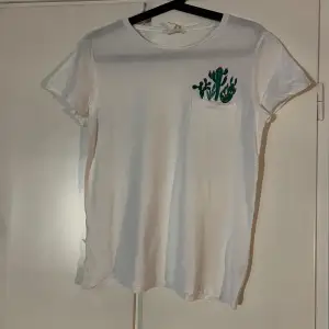 Vit t-shirt med broderade gröna kaktusar i fickan