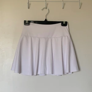 Vit kjol - Vit utsvängd kjol med insydda shorts med en ficka på sidan av benet. Storlek S med stretchigt tyg (träningstyg). Super skön men tyvärr för stor för mig.
