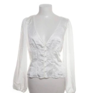 Vit blus - Vit, vringad blus med knappar och knyt på ryggen. Köpt från H&M, bra skick, storlek M men borde passa S också. Jättefin till ex: kjol m.m. Skriv gärna vid intresse eller eventuella frågor😊