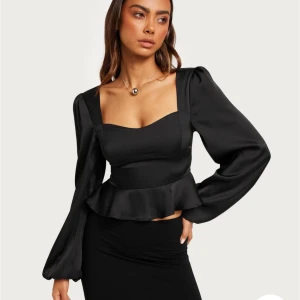 Fest topp från Nelly  - Oanvänd topp från Nelly. Prislappen borttagen. Svart satin festtopp Säljer pga att den aldrig kommit till användning.  Nypris 399 kr, säljer för 200 kr