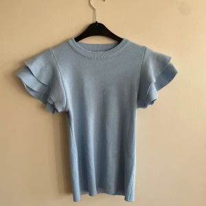 Blå tröja  - Ljusblå tröja med volang ärmar 