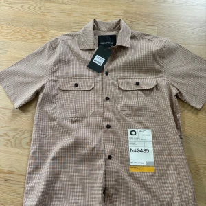 Skjorta Catepillar - Skjorta från Catepillar med lapparna kvar! Supercool med fina färger.  Det som ser ut som lapp på höger sida är ett print. 