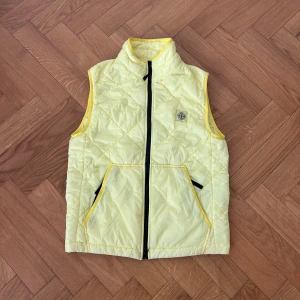 Stone island väst - Snygg väst i skön gul färg, mycket bra skick förutom en liten fläck (se bild). Nypris 3500