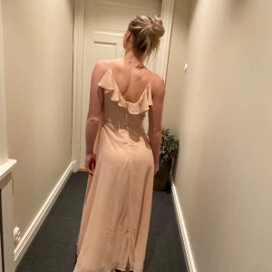 Rosa långklänning💕 - Rosa långklänning som inte kommer till användning💕 Perfekt till brölopp, dop mm.  Strl 36-38, min syster på bilden är ca 166cm lång och den går ungefär till hennes fotknölar.  Volanger och dragkedja i ryggen💕 Köparen står för eventuell frakt🤍