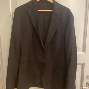 Brun Kavaj i Ull - Herr  - Storlek: 50 (herr) Material: Ull m.m.  Färg: Brun Ej konstruerade axlar. Sparsamt använd (handfull gånger endast)  