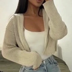 Croppad Zara cardigan - Detta är en lite kortare cardigan (kofta) köpt på zara för 399. Den har aldrig använts utan bara testats och är i helt nytt skick. Den är ljus beige och passar super bra till ett par jeans eller svarta kostymbyxor. Hör av er vid eventuella frågor!