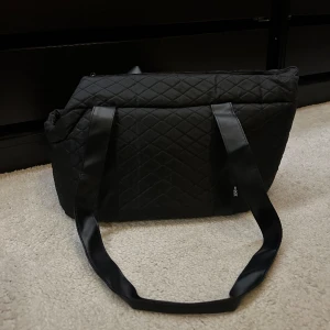 Hundväska  - Hundväska, svart. Helt ny. Klarar upp till ca 8kg. 40x30cm, fast bottnen och robusta väggar samt remmar.  Spänne för halsband i.  
