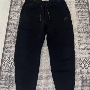 Nike tech byxor svarta - Säljer ett par fina nike tech byxor svarta, de är i mycket bra skick och har använts sparsamt vid frågor är det bara att höra av er :)