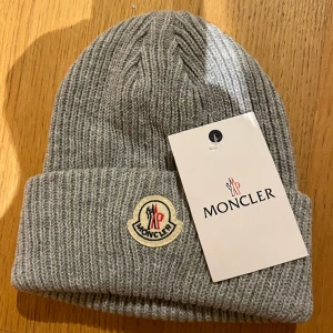 Moncler mössa - Perfekt skick med plastpåse över samt tags, har 1 i denna färg. Skriv privat för frågor! (Grå)