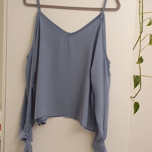 Ljusblå topp - Superfin gråblå färg. Nyskick. Fina knytdetaljer på ärmarna