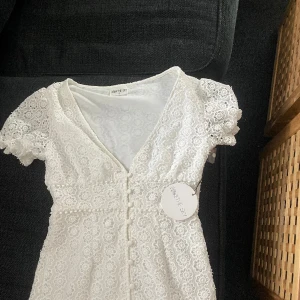 Vit klänning (student) - En jätte gullig sommar kläning som passar som en studentklänning. Den är för lång och för stor i bysten för mig som är 157 cm lång. Jag köpte den från Nelly för längesedan fden är ej använd prislapp sitter kvar🥰 