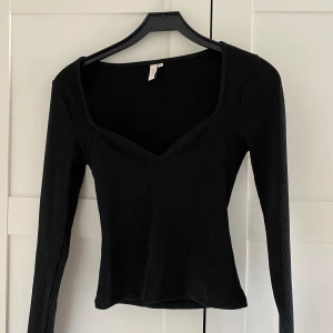 Långärmad topp  - En svart långärmad ribbad topp med fin urringning från Nelly. Toppen är använd 1 gång.  