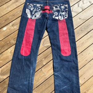 Jeans Evisu - Jeans: Evisu Paris #5001. Använt skick så trycket är lite blekt och de har en pytteliten reva, men annars hela och fina! Storlek 38 i midja (och jag gissar 34 el 36 i längd).