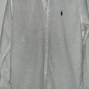 Vit Polo ralph lauren linne skjorta - Vit vara som används fåtal gånger, suttit i garderoben och vill bli av med den. Storlek L men passar mindre och är linne material
