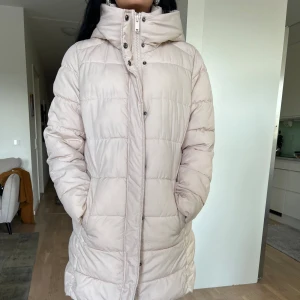 Vacker Höst/Vinter Jacka HM -  Varm och snygg H&M-dunjacka i ljusrosa, storlek Medium. Perfekt för kalla vinterdagar med praktisk huva och modern design. Dragkedja och knäppning för extra skydd. Använd få gånger, mycket gott skick.