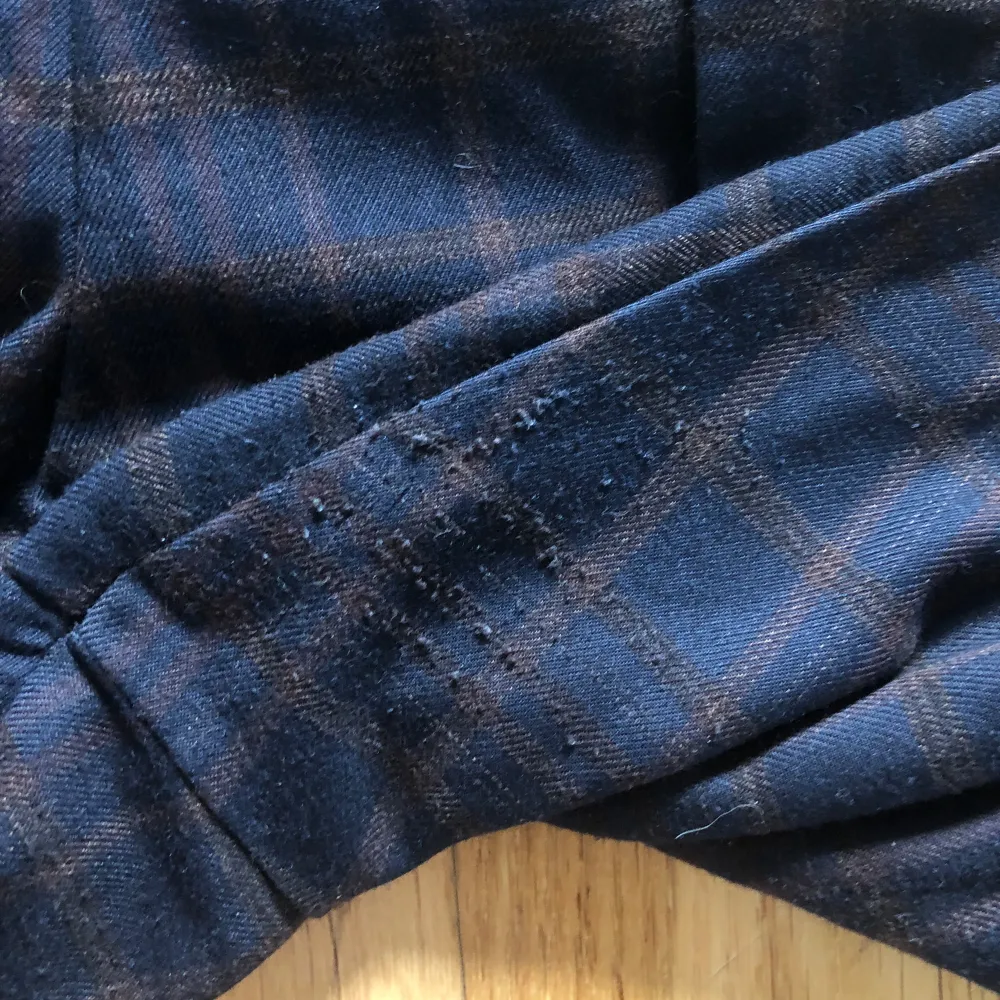Ett par mörka, rutiga paper bag-byxor i storlek 42/L/XL från H&M. Nypris runt 149 kr. Passar mig som har L-XL i byxstorlek samt perfekt längd (jag är 162 cm kort för referens.) Använda men i gott skick förutom lite noppror i skrevet (se bild 4.) . Farkut & Housut.