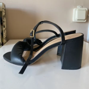 Klackar med ’blockheel’ - Klackskor svarta med ganska bred klack och padded framme vid tån. Bekväma att ha på sig och passar som en normal 37a, knappt använda.