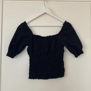 Topp - Svart topp med ruffles runt midjan och puffiga ärmar, superfin!