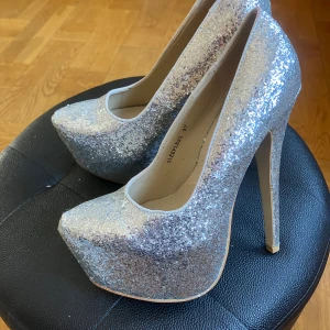 Glittriga högklackade skor - Silvriga högklackade skor i storlek 37. Fint skick.